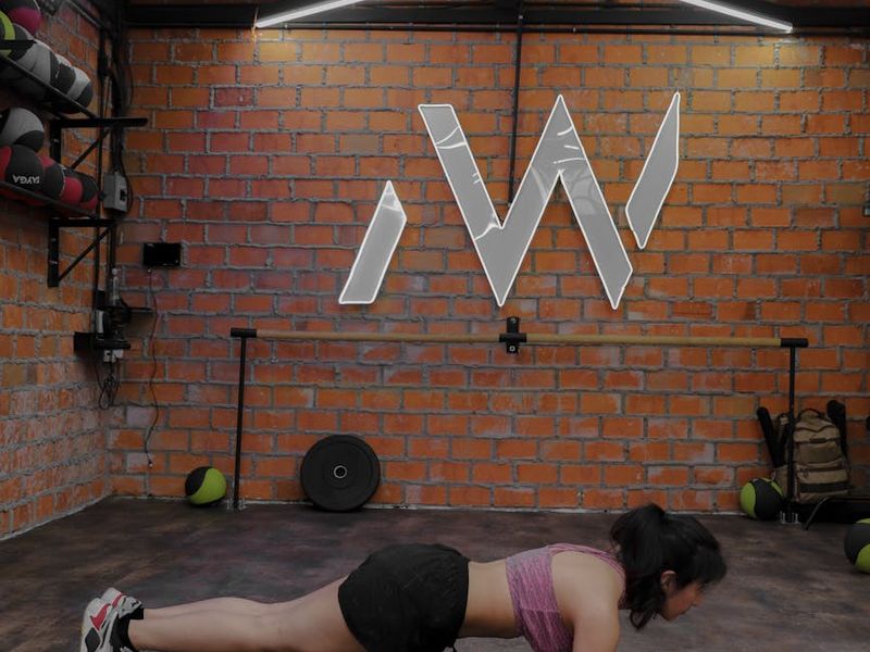 Man performing a controlled plank exercise on a dark mat.